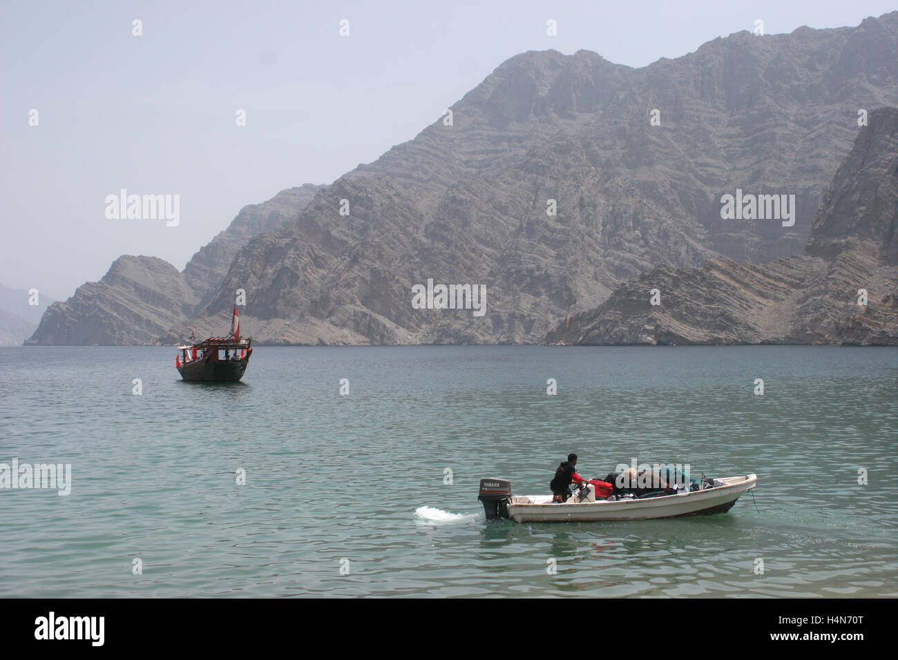 The wild landscape of the Musandam Peninsular at Khasab in northern Oman. Shows local fisheman and tourist dhow Stock Photo