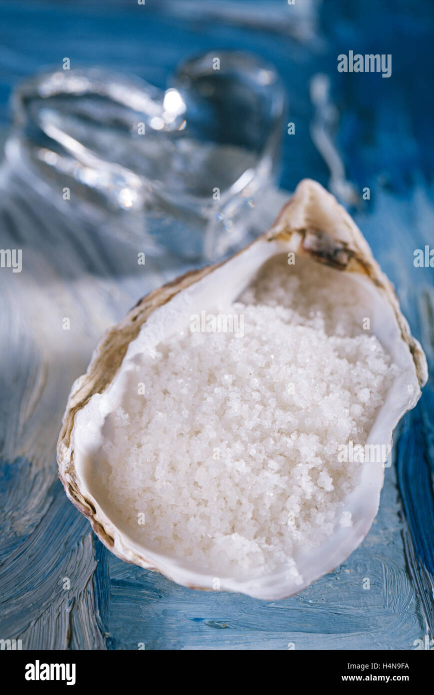 Blue persian sea salt in sea shell oyster and heart glass on blue