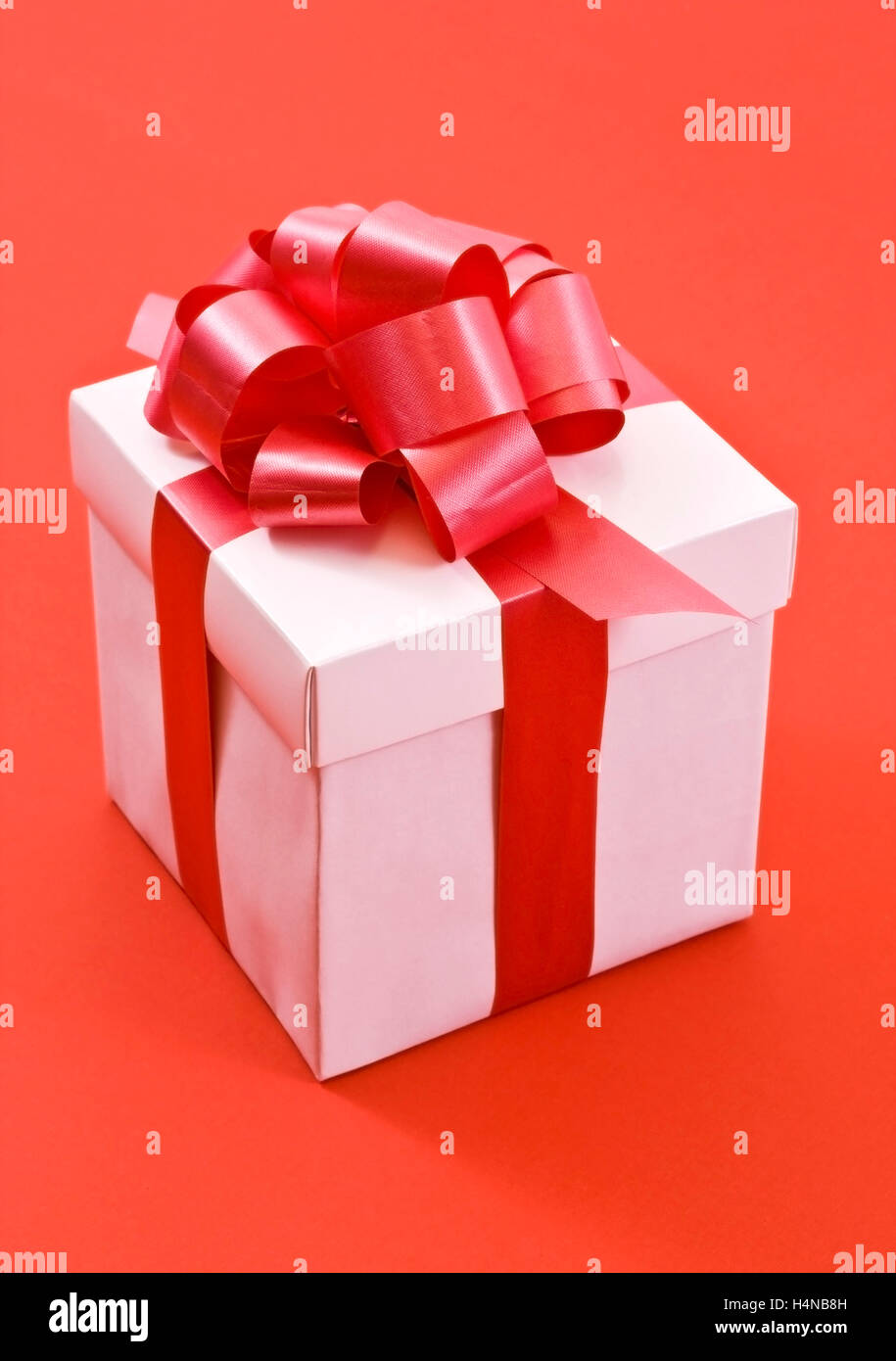 A white box tied with a red satin ribbon bow. A gift for Christmas ...