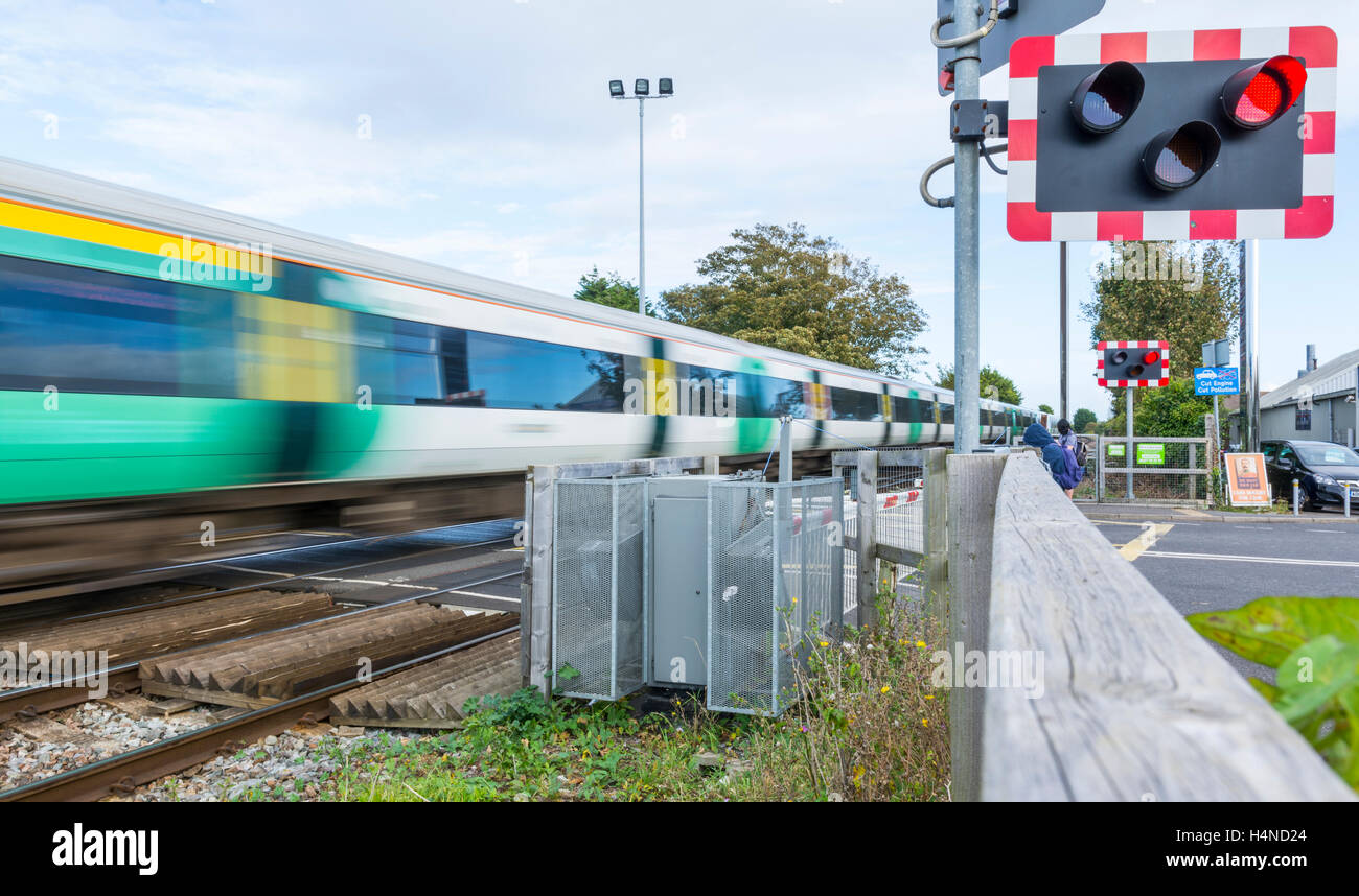 Southern Rail train showing motion blur moving over a level crossing in Southern UK. Southern train. Southern trains. Stock Photo