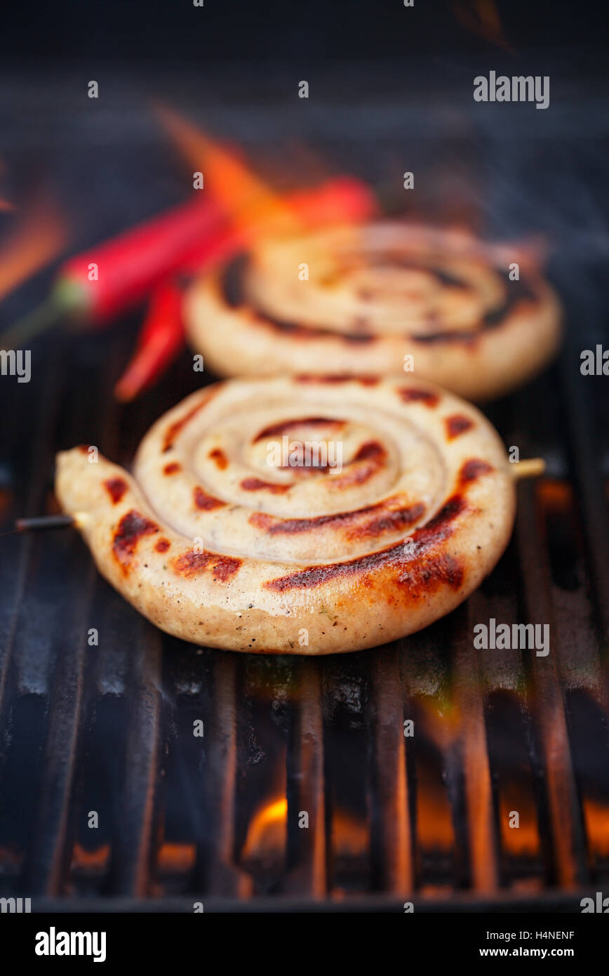 cumberland sausage, spiral pork sausage on bbq grill with flame, homemade Stock Photo