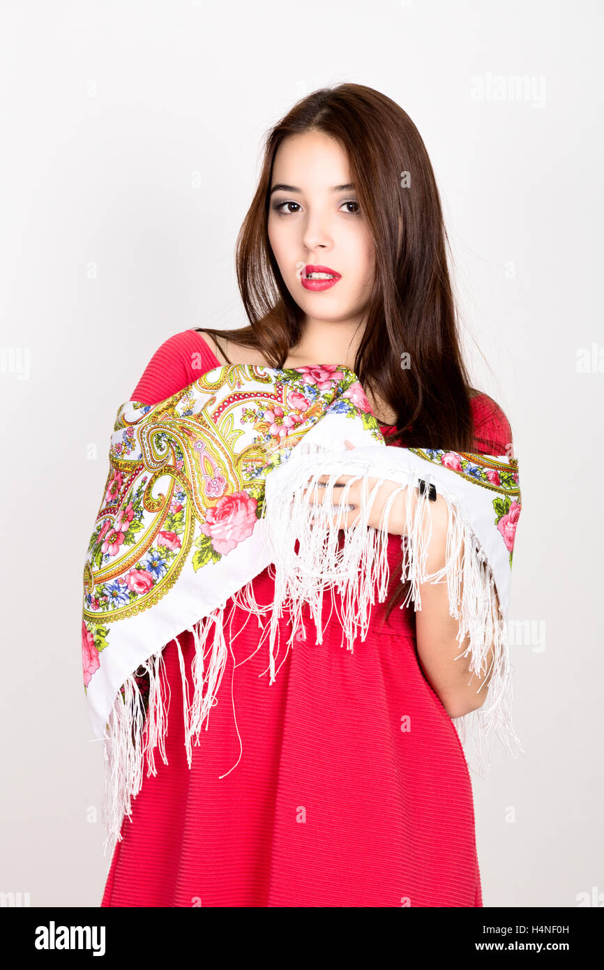 beautiful young woman dressed in a red dress and colored scarf posing