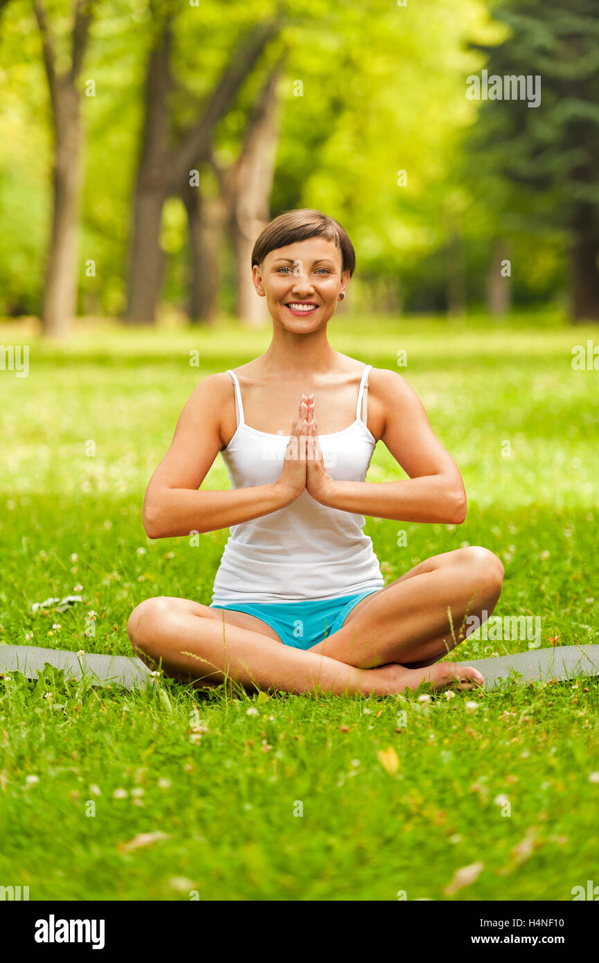 Happy young woman sitting outdoors in yoga position Stock Photo - Alamy