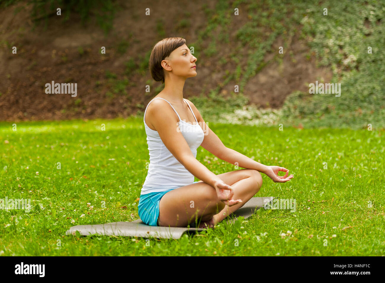 Happy young woman sitting outdoors in yoga position Stock Photo - Alamy