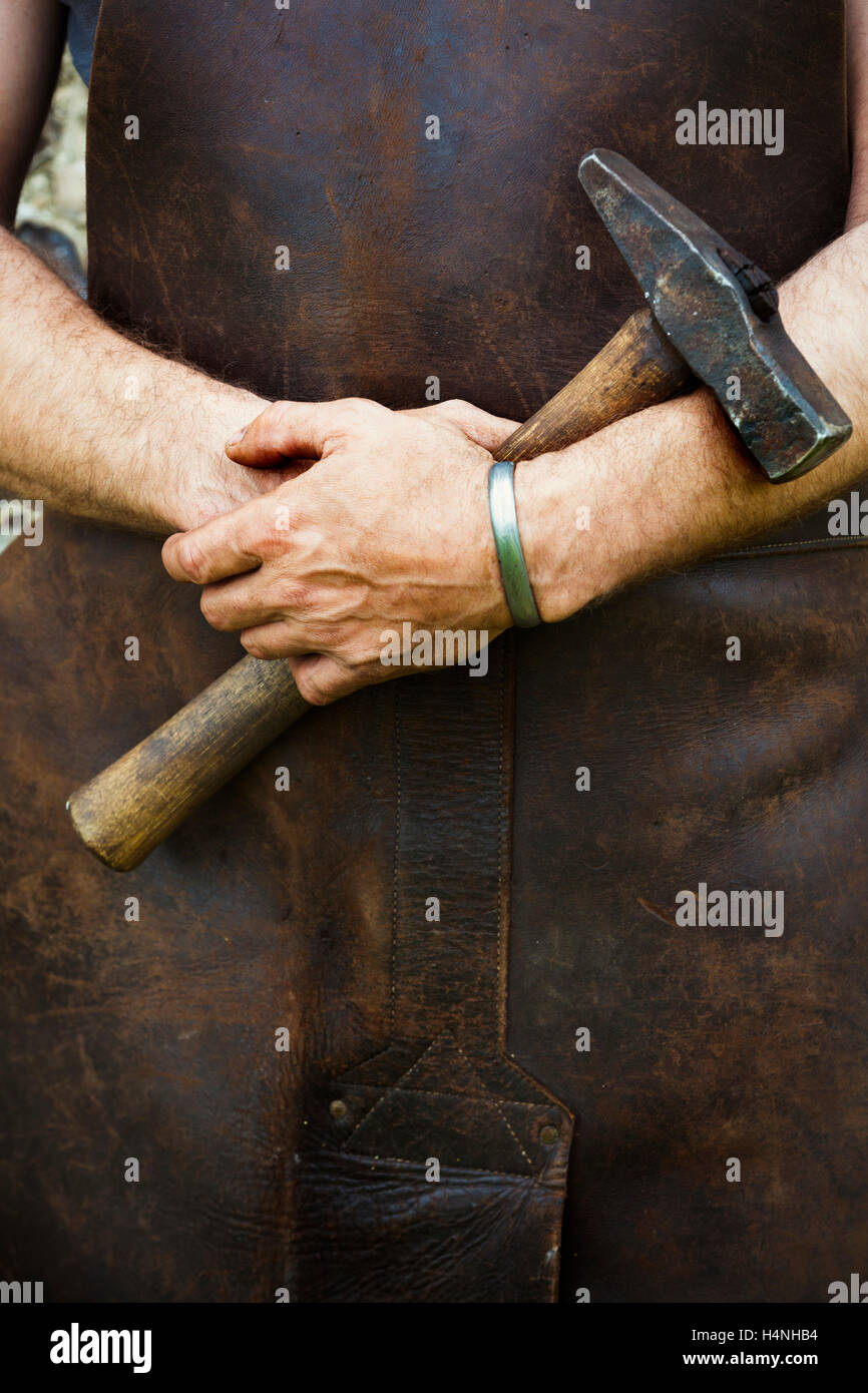 Man in a leather apron holding a hammer Stock Photo Alamy