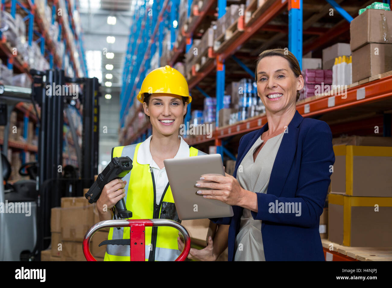 Warehouse manager and female worker smiling while holding digital tablet Stock Photo