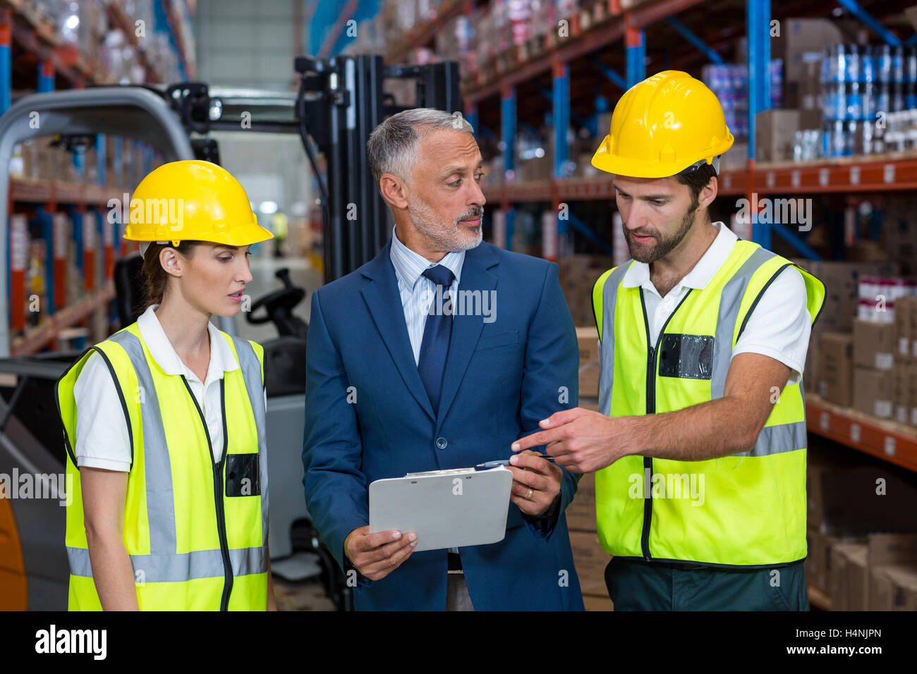 Warehouse manager and co-workers discussing over clipboard Stock Photo