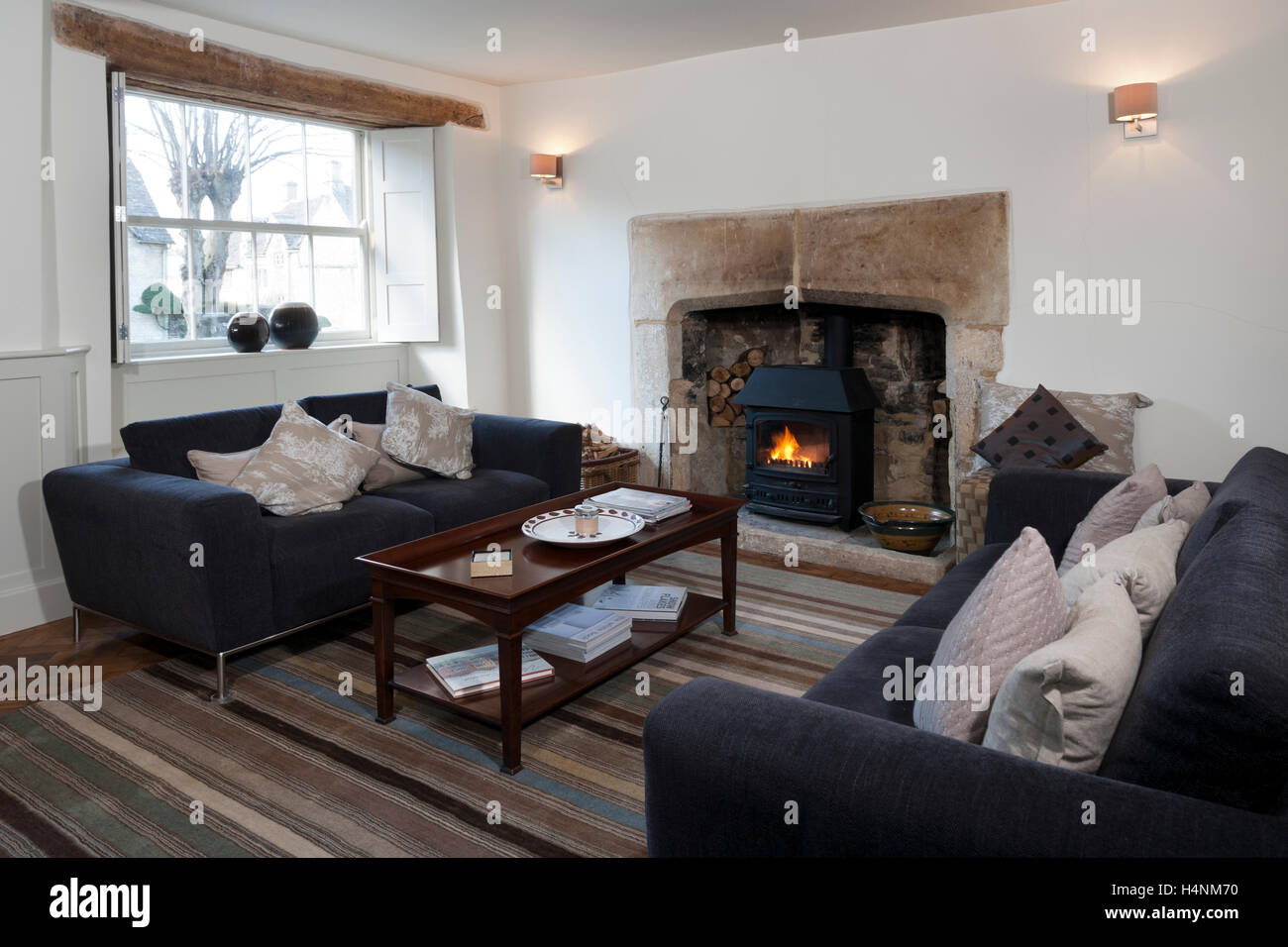 A simply firnished living room with a period fireplace feature and a log burning stove Stock Photo
