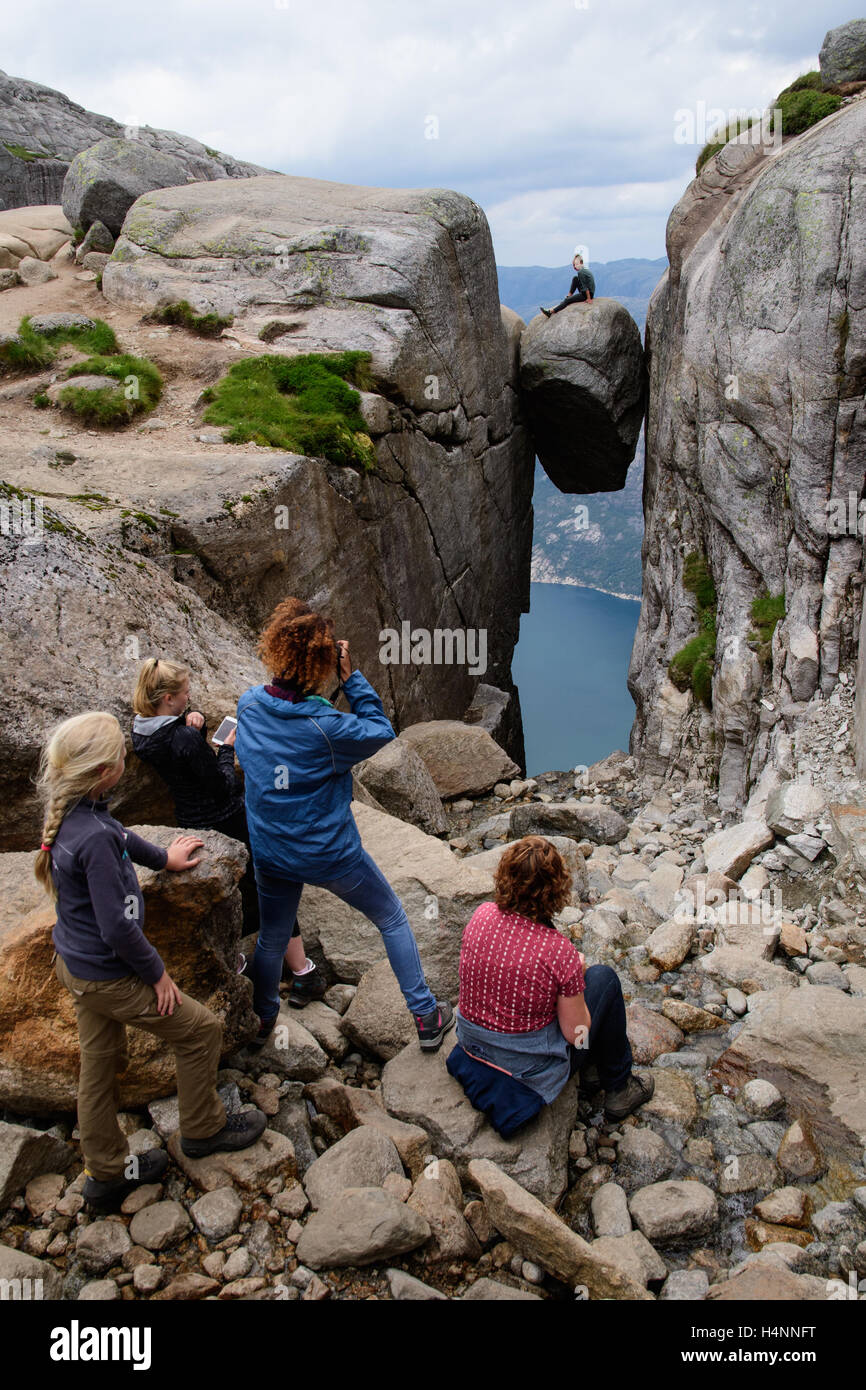 Tourists taking photos of friends on Kjeragbolten, a rock hanging 1100 meters above the fjord Lysefjorden, Norway Stock Photo