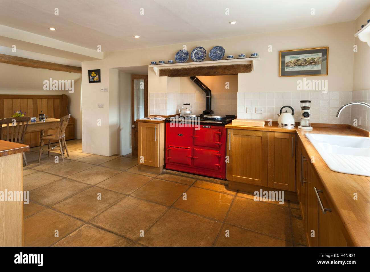 A simple wooden finished fitted kitchen with a vibrant red Aga range cooker focal point. Stock Photo
