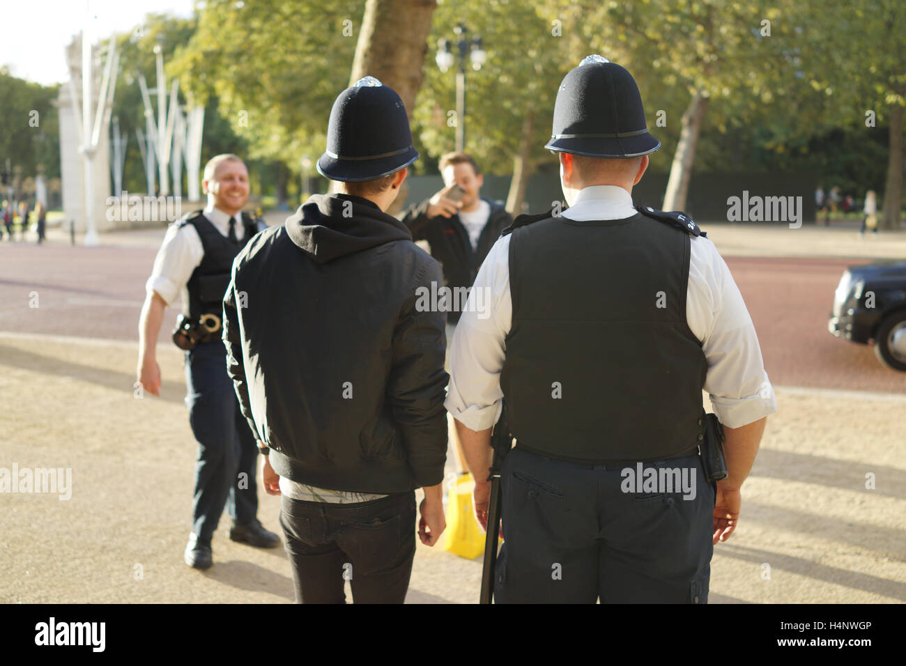 Friendly policeman lends his hat to a tourist in London Stock Photo