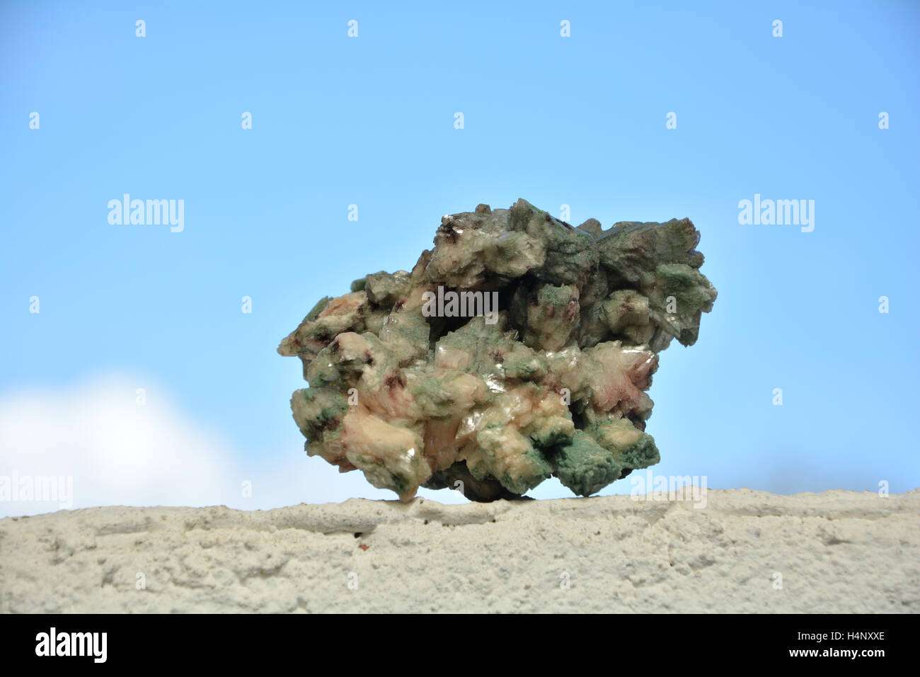 Green minerals stone on white wall  against a blue sky Stock Photo
