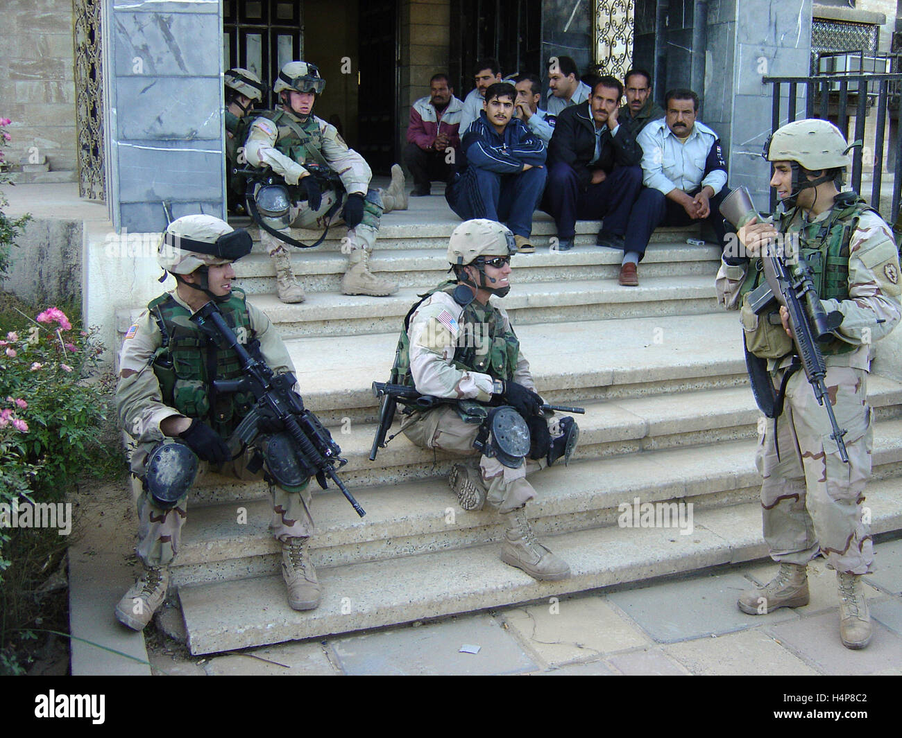 3rd December 2004 U.S. Army soldiers of 'Deuce Four' relax with Iraqi policemen outside a police station in Mosul, northern Iraq. Stock Photo