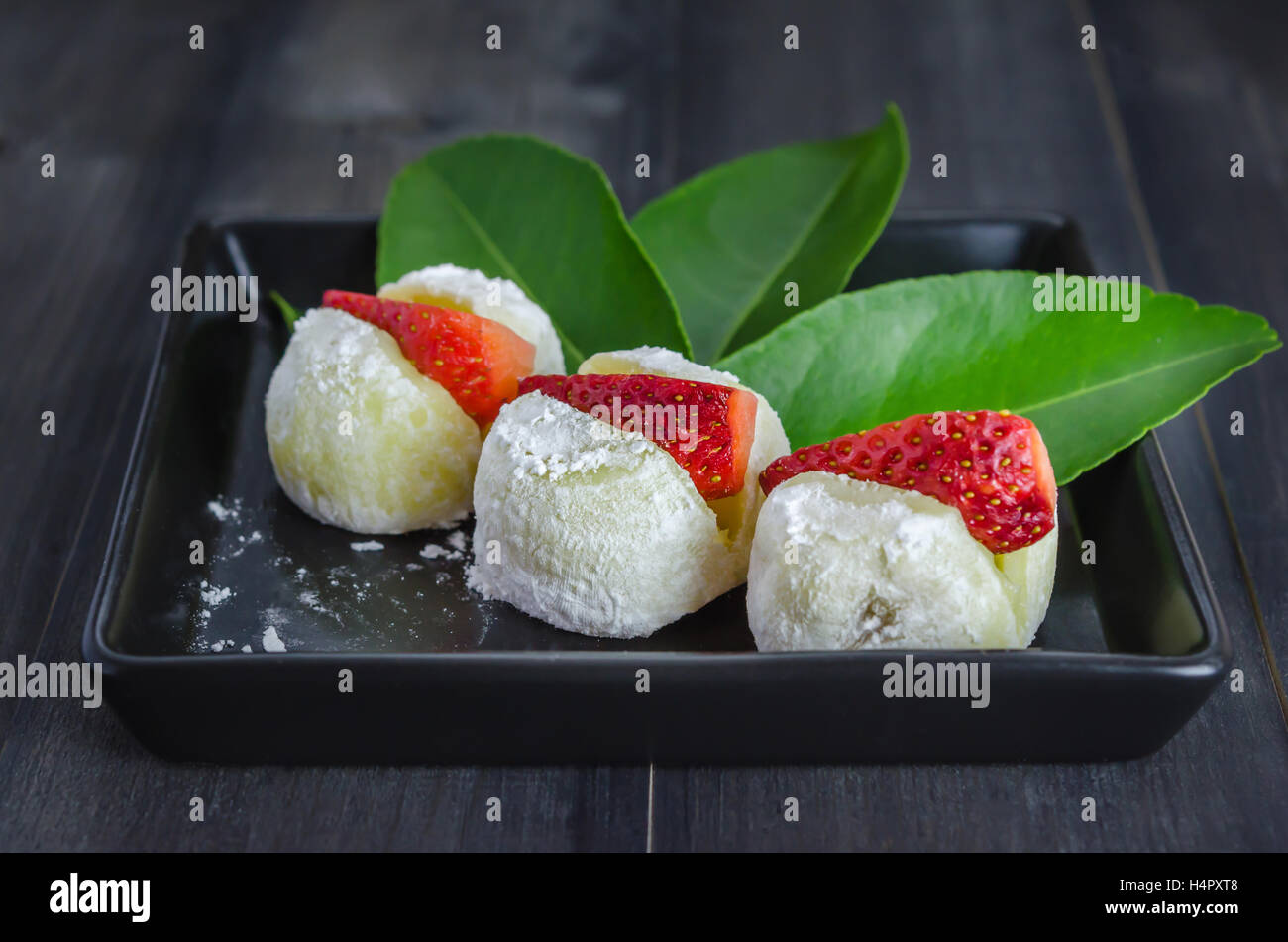 Strawberry Daifuku Mochi Japanese dessert on black dish over wooden background Stock Photo