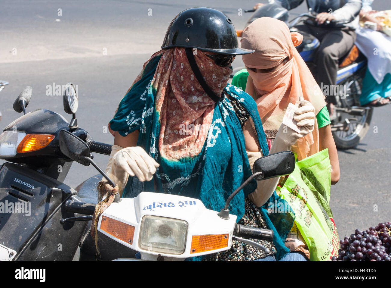 Face and arm covered women, to protect from sun and pollution, riding  driving on a scooter in centre of Ahmedabad,Gujurat Stock Photo - Alamy