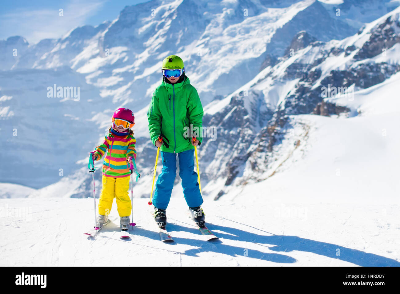 Kids skiing in mountains. Active children with safety helmet, goggles and poles. Ski race for young kids. Winter sport Stock Photo