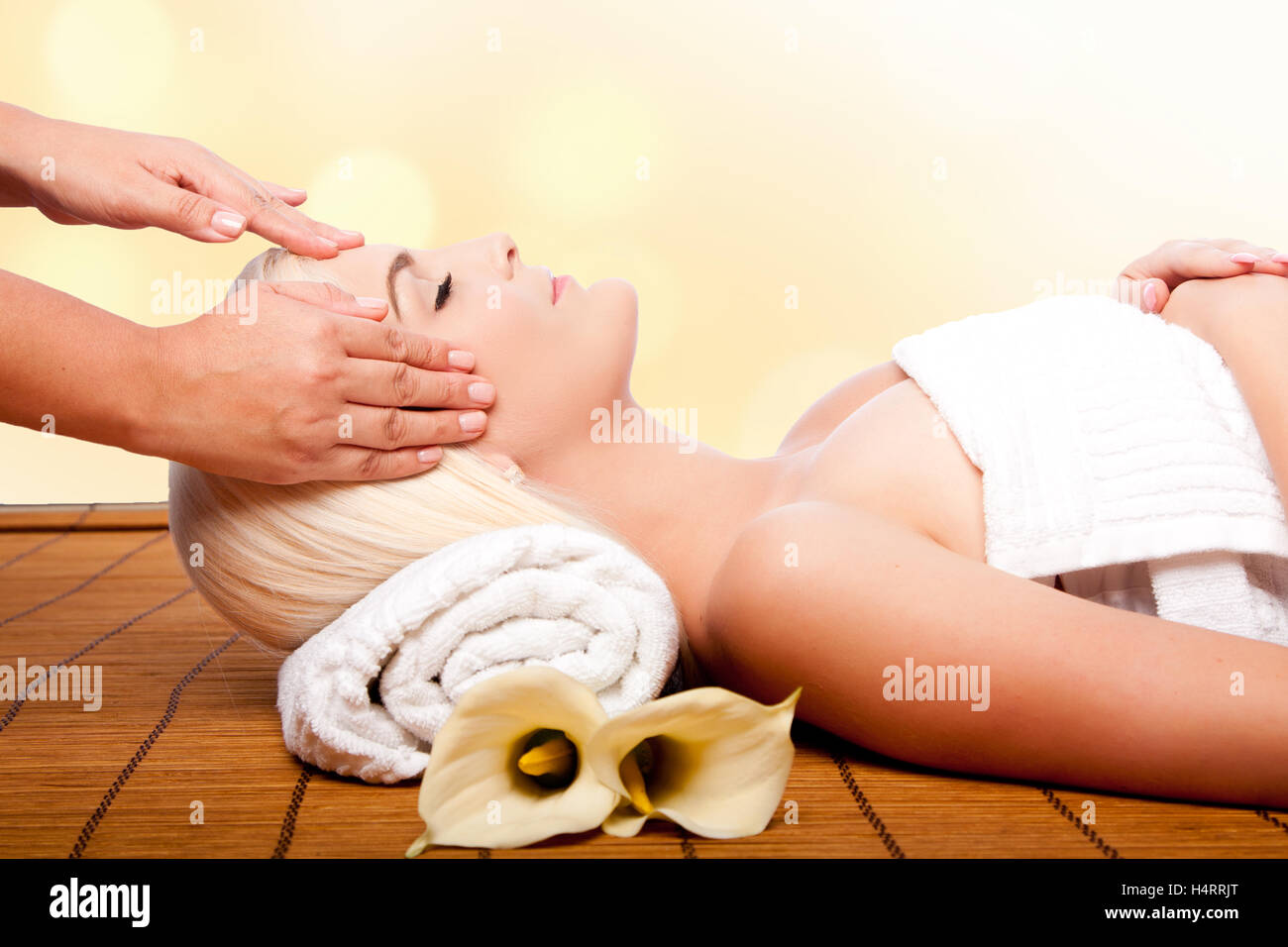 Beautiful young woman relaxing at spa getting therapeutic pampering forehead massage. Stock Photo