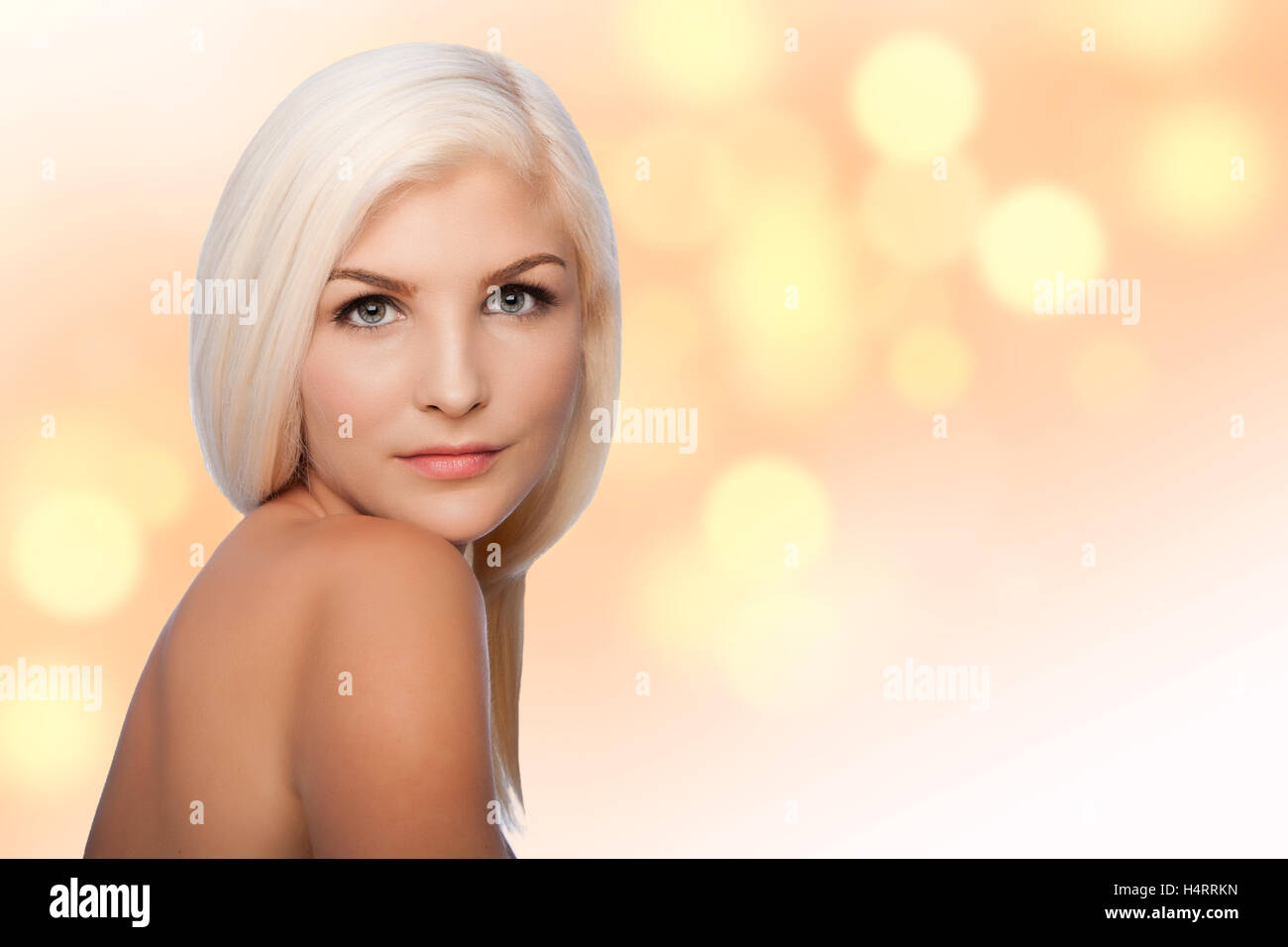 Beautiful face of young woman for Aesthetics facial skincare concept looking over shoulder, on blurred lights background. Stock Photo