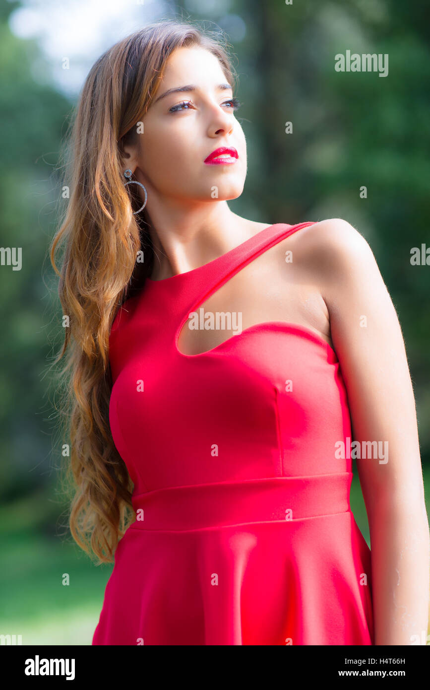 Beautiful girl with red dress looks into the sun Stock Photo Alamy