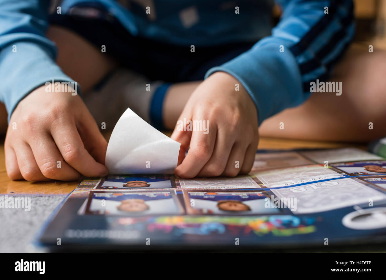 An 8 year old boy is pasting football trading cards into his sticker collection scrapbook. Stock Photo