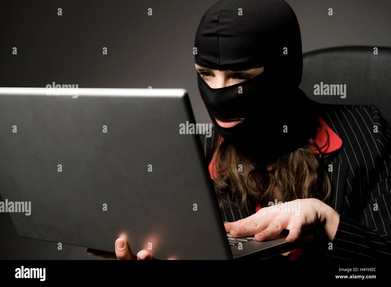 Masked burglar with laptop, economic espionage, data piracy Stock Photo
