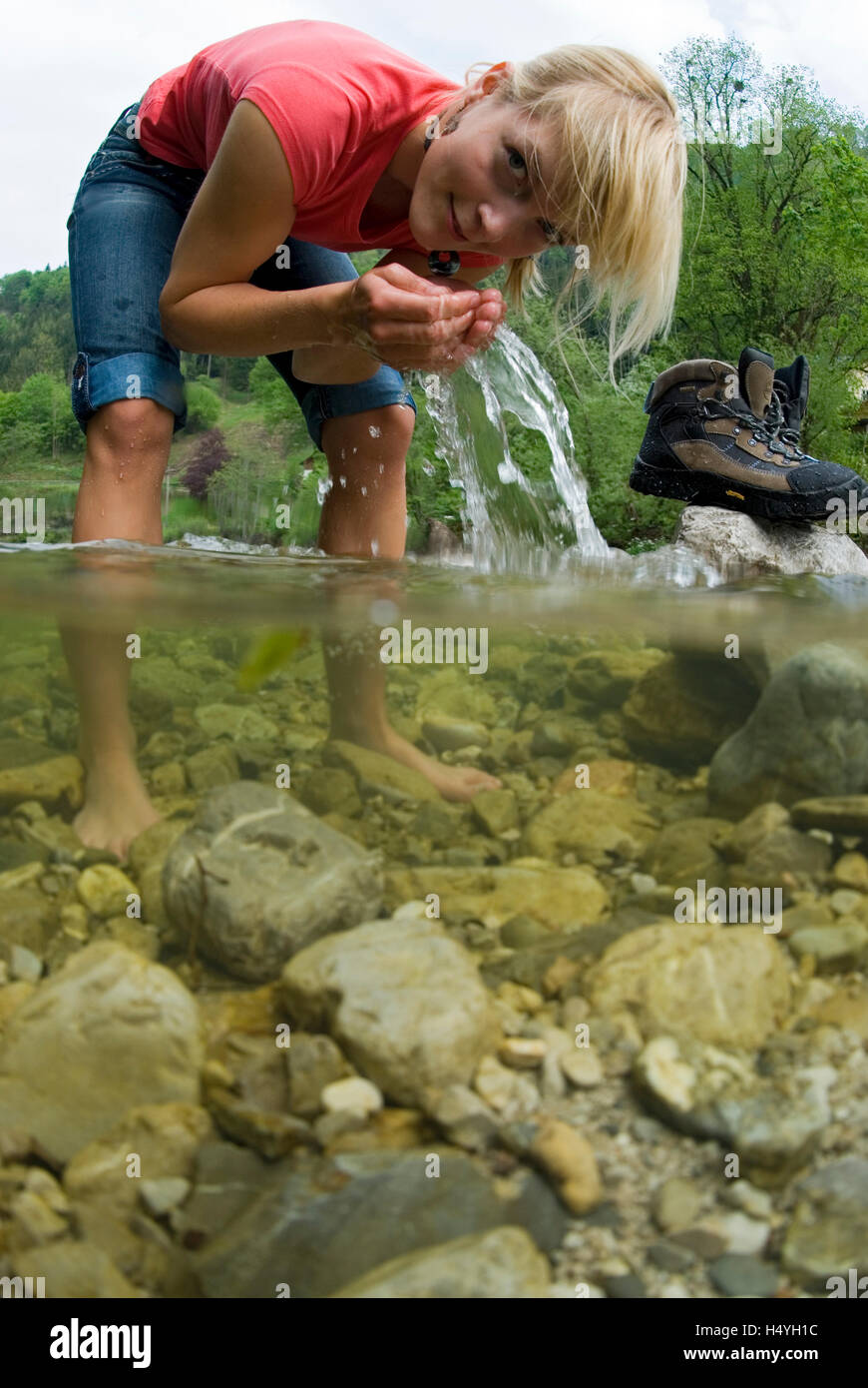 Woman standing in a mountain stream and refreshing herself Stock Photo