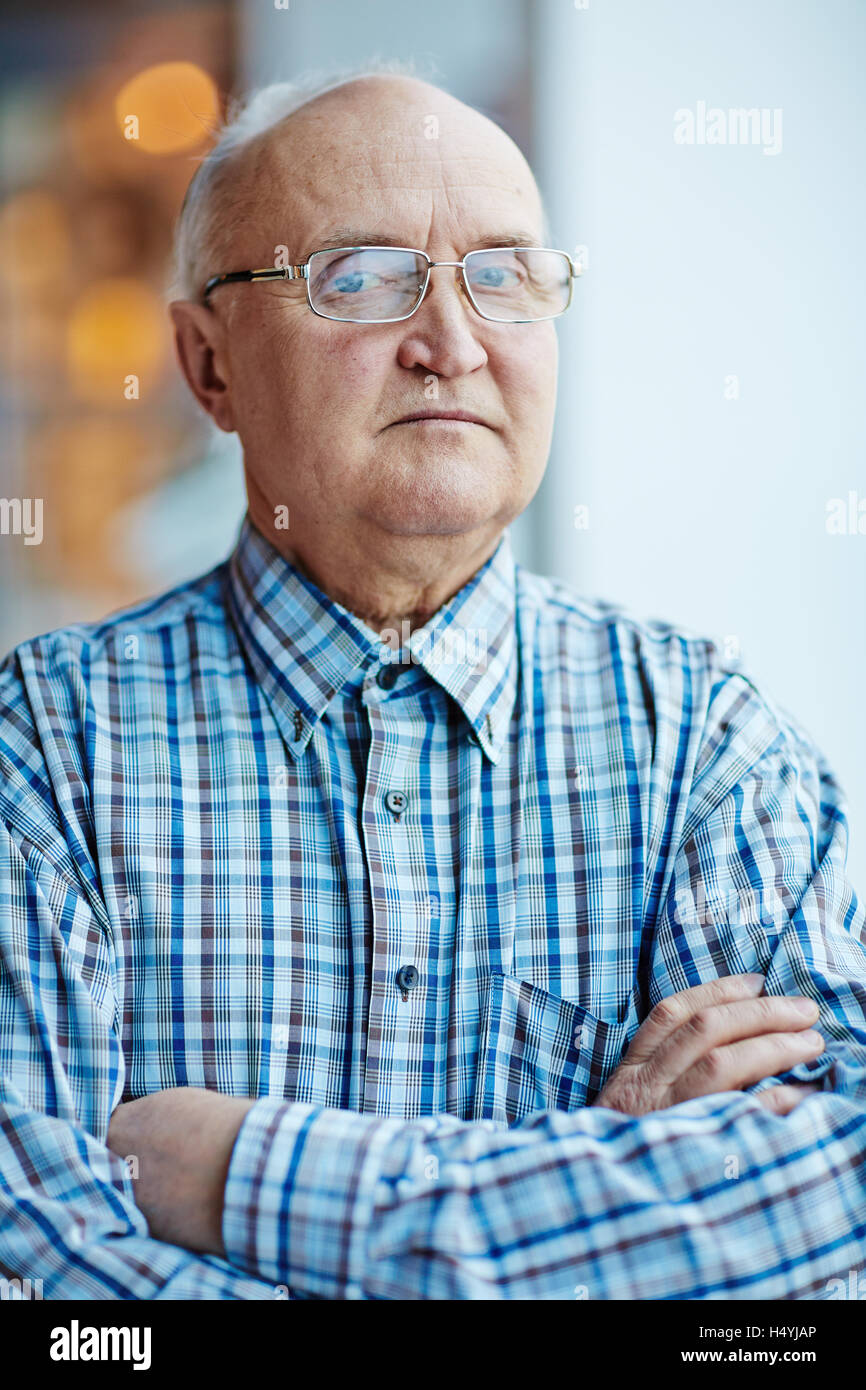 Retired cross-armed man looking at camera Stock Photo