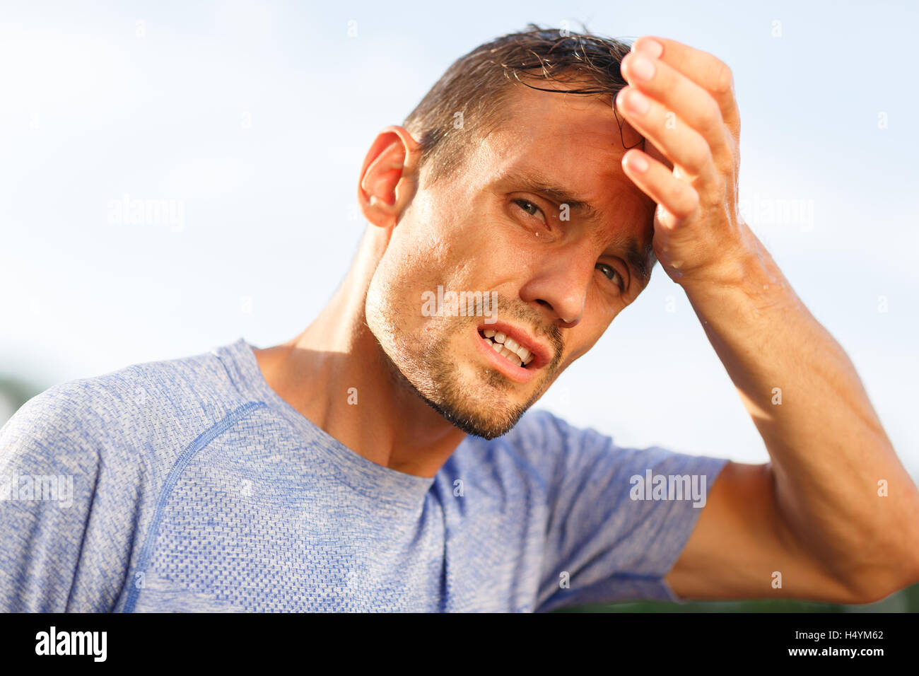 Sporty man closeup wipes forehead with his palm Stock Photo