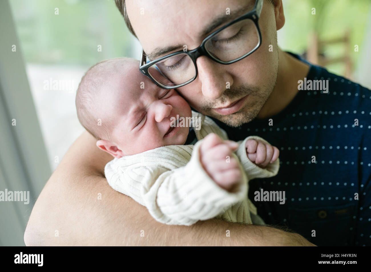 Young father holding his newborn baby son in his arms Stock Photo
