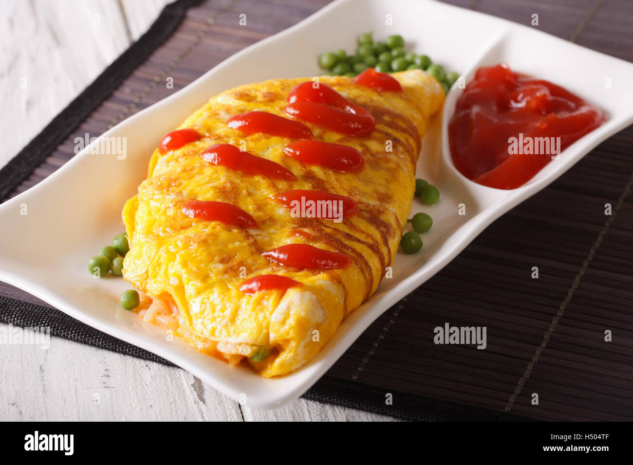 Delicious Omurice omelette with ketchup close-up on a plate. Horizontal Stock Photo