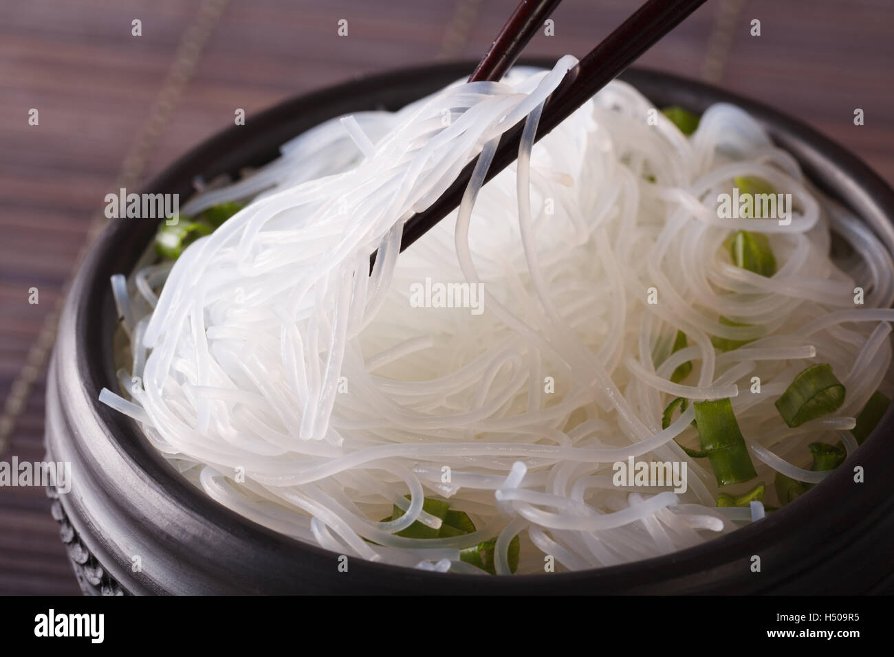 Glass noodles with green onions in a bowl macro on the table. horizontal Stock Photo