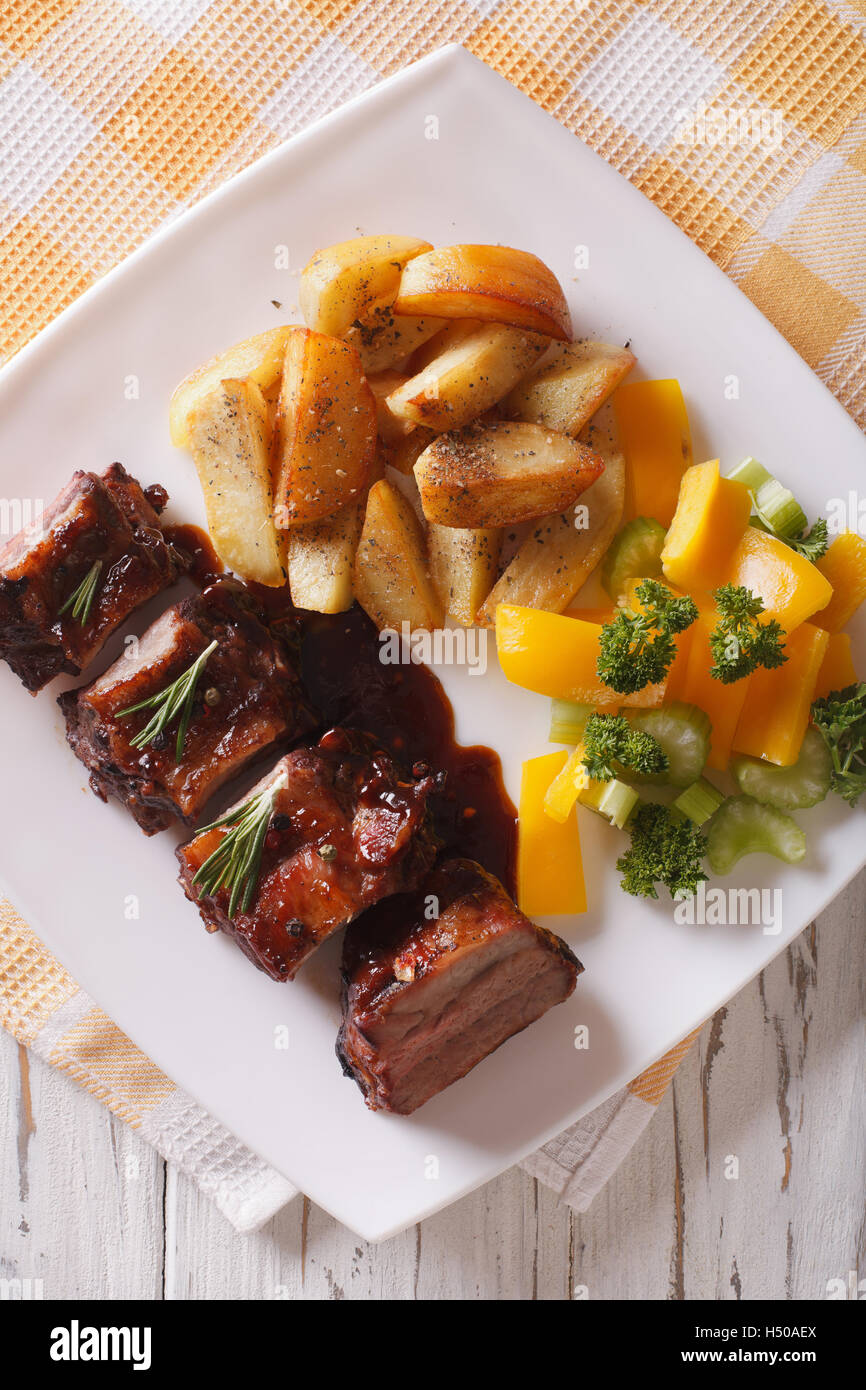 BBQ pork ribs with a side dish of vegetables close-up on a plate ...