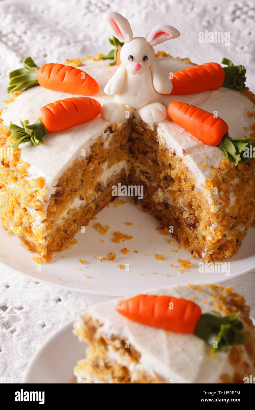 carrot cake decorated with bunny and slice close-up on the table. vertical Stock Photo