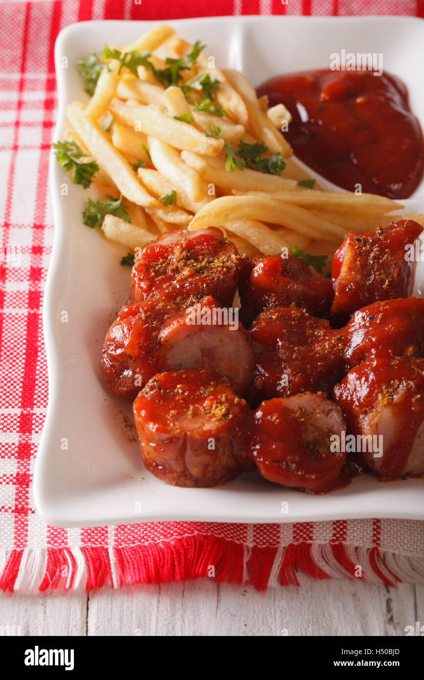 Currywurst sausage with french fries close-up on a plate. vertical Stock Photo
