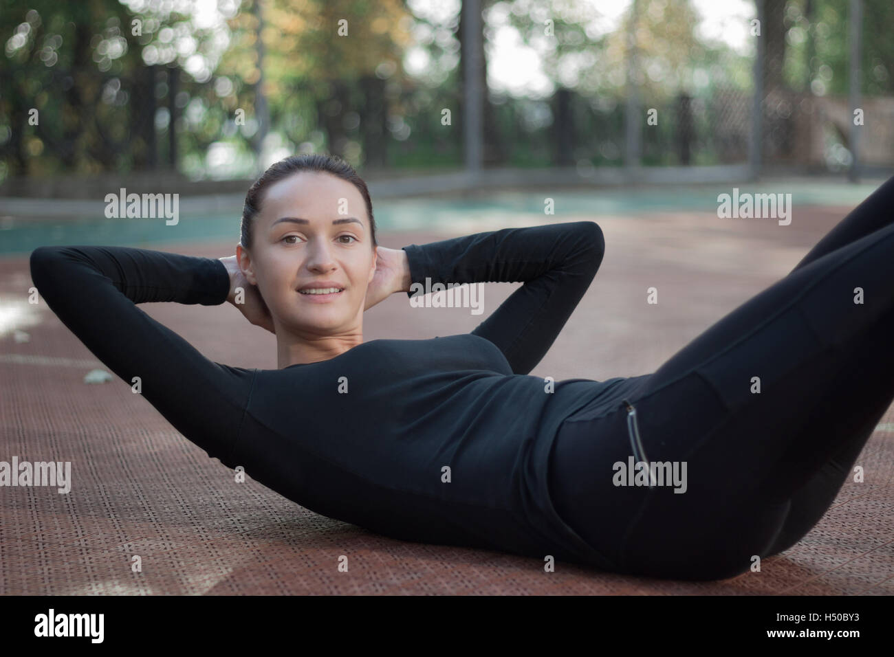 Young pretty fitness woman exercises during morning sport training workout on playground outdoor Stock Photo