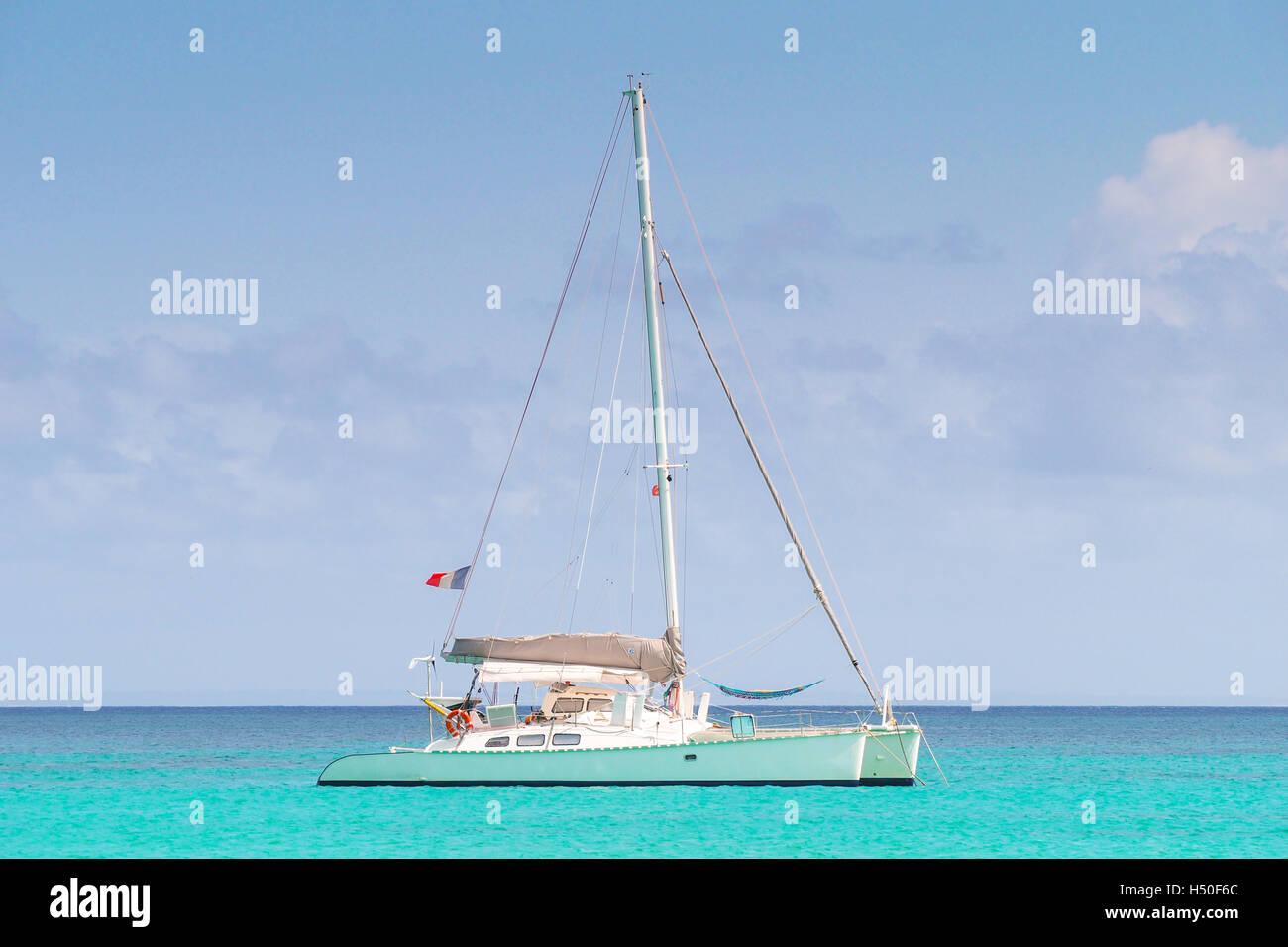 Catamaran with french flag anchored in a turquoise caribbean sea. Stock Photo