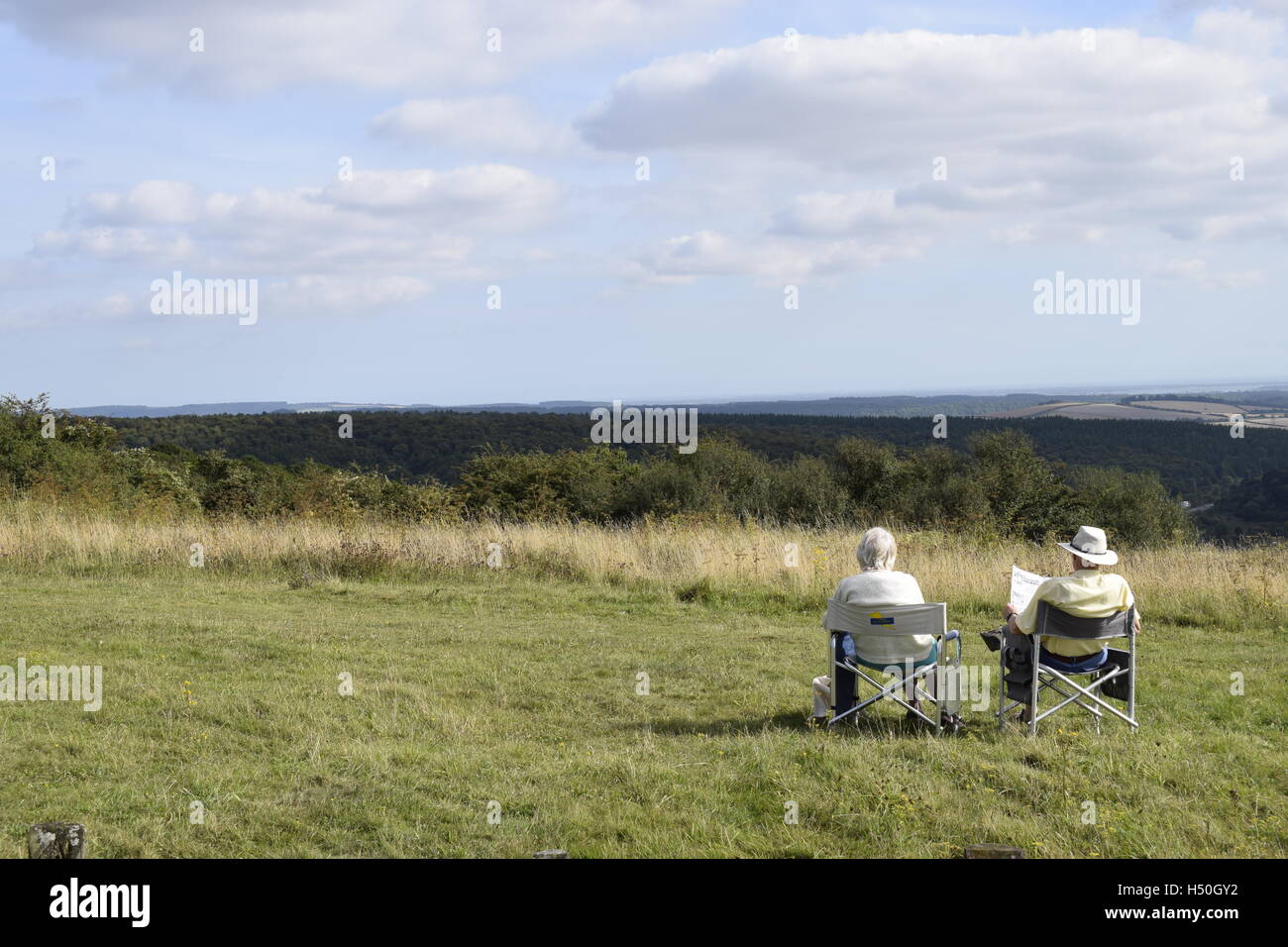 An elderly couple relax in camping chairs on the South Downs Stock Photo