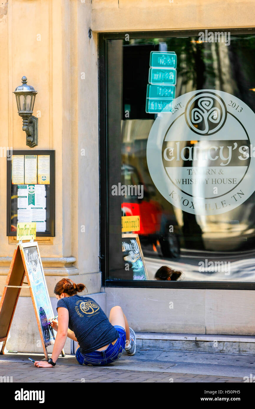 Female outside Clancy's Tavern in Knoxville, TN, writing todays menu on