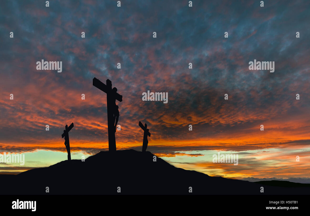 A silhouette of the crucifixion of Jesus Christ on a cross with 2 other robbers against a dramatic sunset. Stock Photo