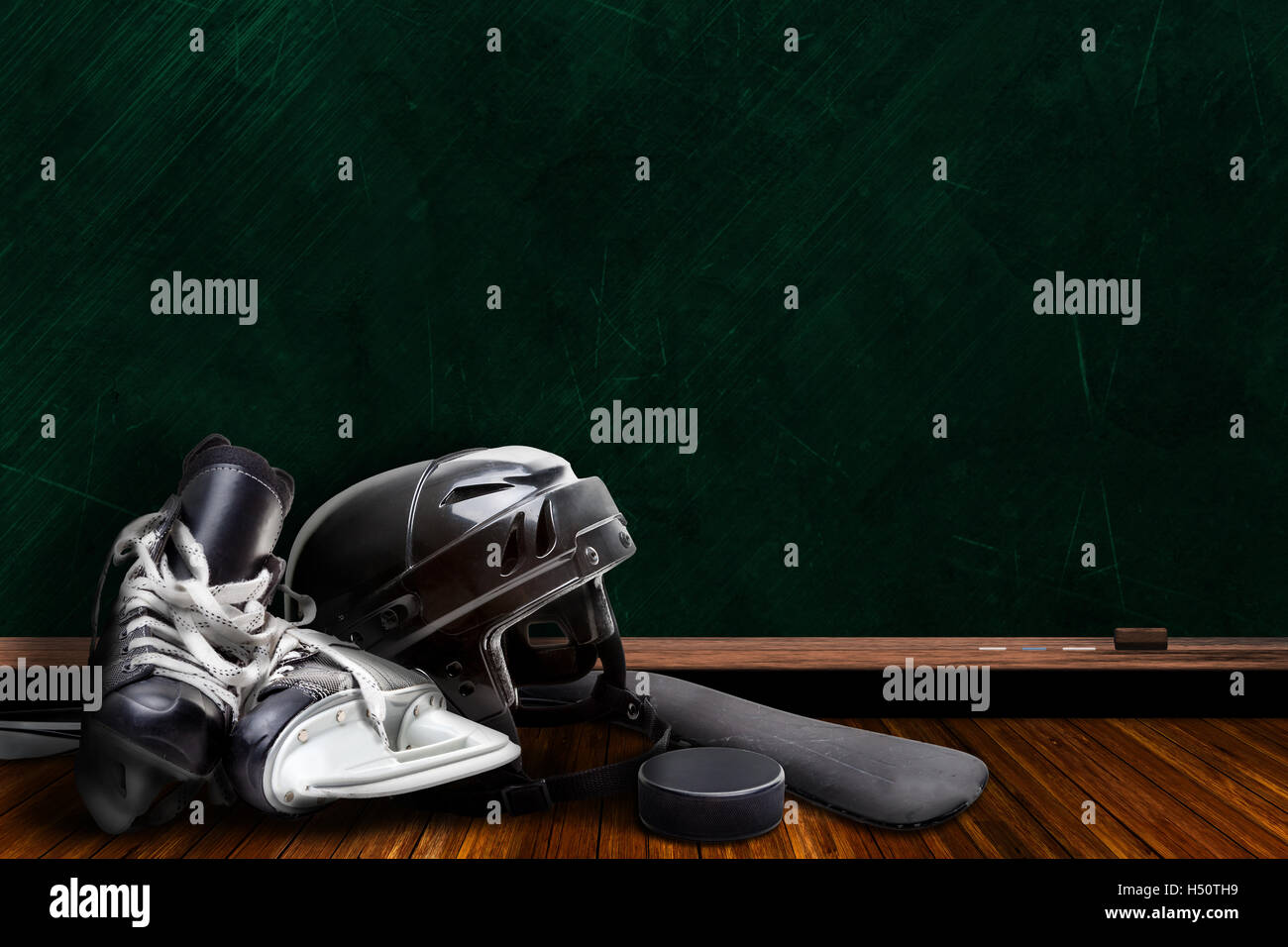 Ice hockey equipment consisting of skates, helmet, stick and puck with background chalk board copy space. Stock Photo