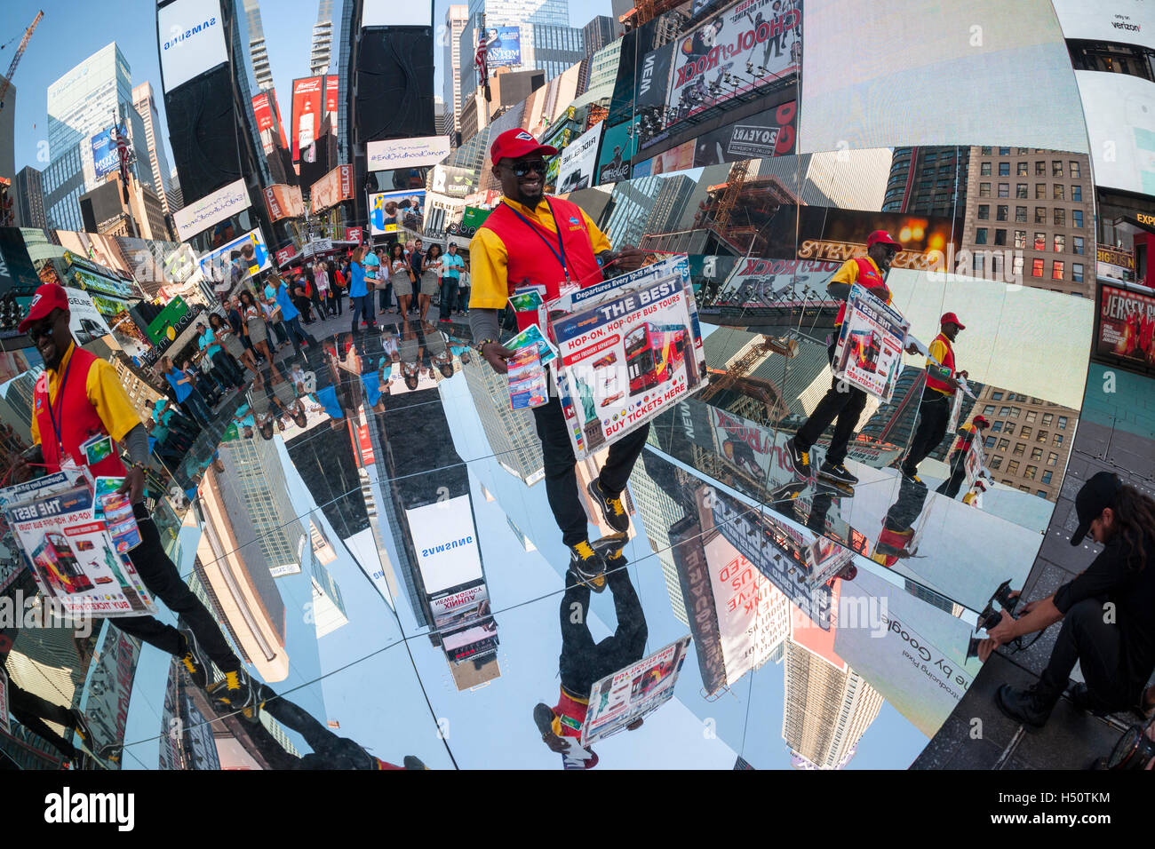 Gray Line ticket seller Saami Ibrahim walks through the mirrored artwork, 'The Beginning of the End' by the Cuban artist Rachel Valdés Camejo at its unveiling in Times Square in New York on Tuesday, October 18 2016.  The sculpture of three mirrored sides, two wall and a a floor interacts with and multiplies its environment as well as providing a selfie type photo op for tourists. This is Camejo's first solo show in the U.S.  (© Richard B. Levine) Stock Photo