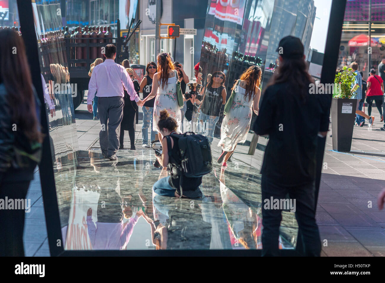 Visitors indulge their inner narcissism as they pose in the mirrored artwork, 'The Beginning of the End' by the Cuban artist Rachel Valdés Camejo at its unveiling in Times Square in New York on Tuesday, October 18 2016.  The sculpture of three mirrored sides, two wall and a a floor interacts with and multiplies its environment as well as providing a selfie type photo op for tourists. This is Camejo's first solo show in the U.S.  (© Richard B. Levine) Stock Photo
