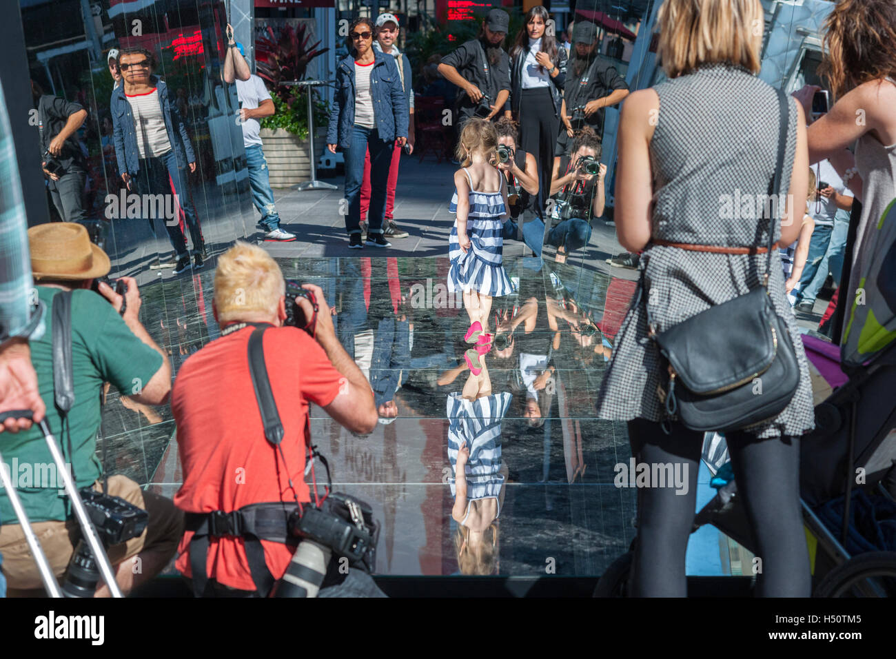 Visitors indulge their inner narcissism as they pose in the mirrored artwork, 'The Beginning of the End' by the Cuban artist Rachel Valdés Camejo at its unveiling in Times Square in New York on Tuesday, October 18 2016.  The sculpture of three mirrored sides, two wall and a a floor interacts with and multiplies its environment as well as providing a selfie type photo op for tourists. This is Camejo's first solo show in the U.S.  (© Richard B. Levine) Stock Photo