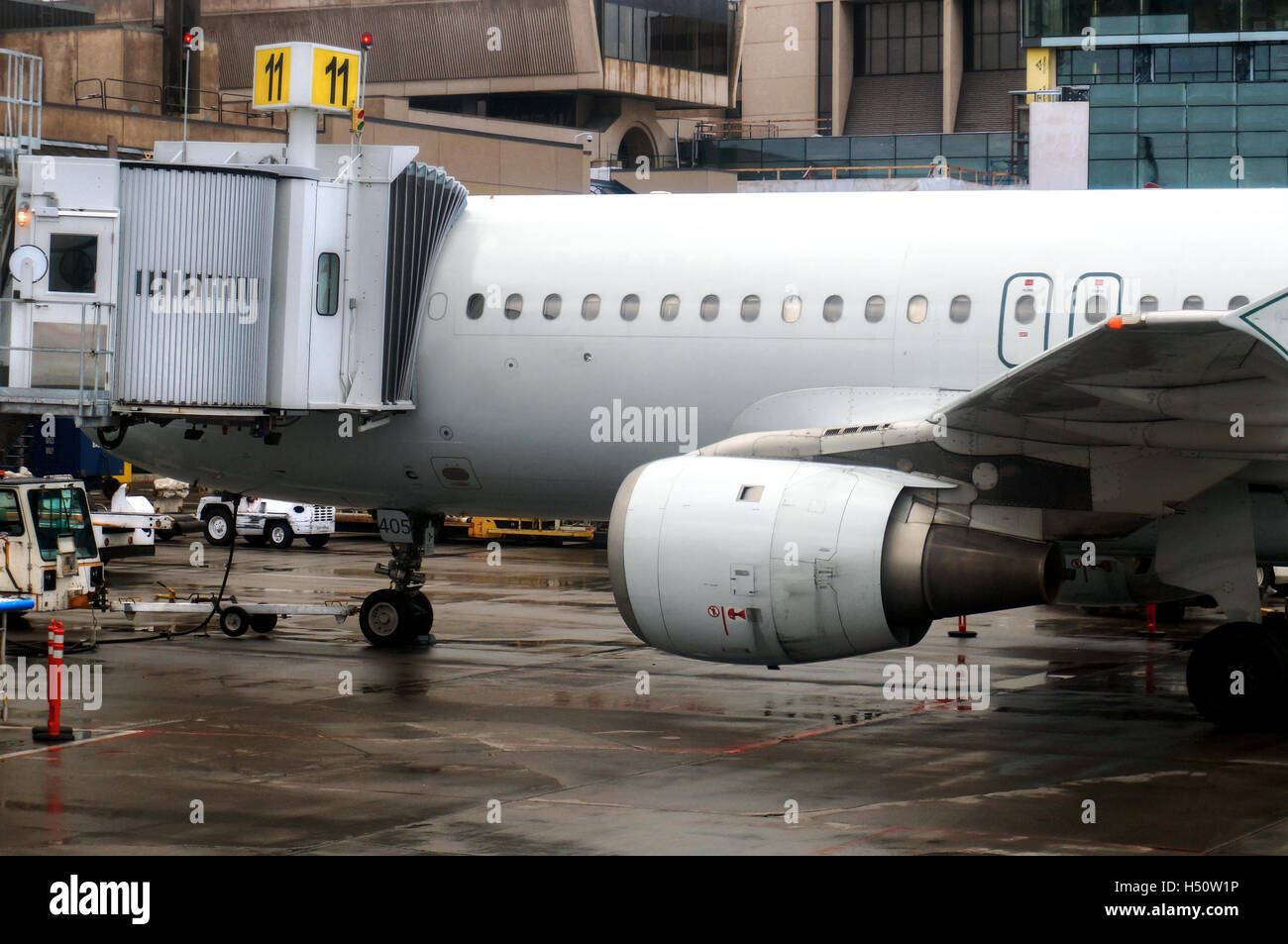 An airplane connected to a jet bridge being serviced at an airport before its next scheduled flight. Stock Photo