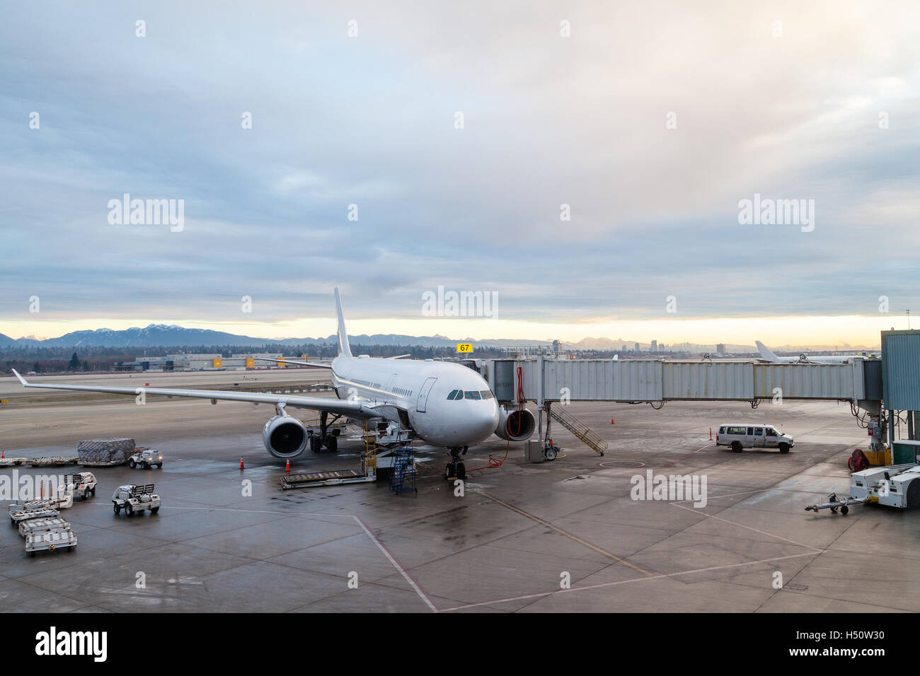 A commercial aircraft on the tarmac being serviced at the passenger terminal of Vancouver International Airport YVR. Stock Photo