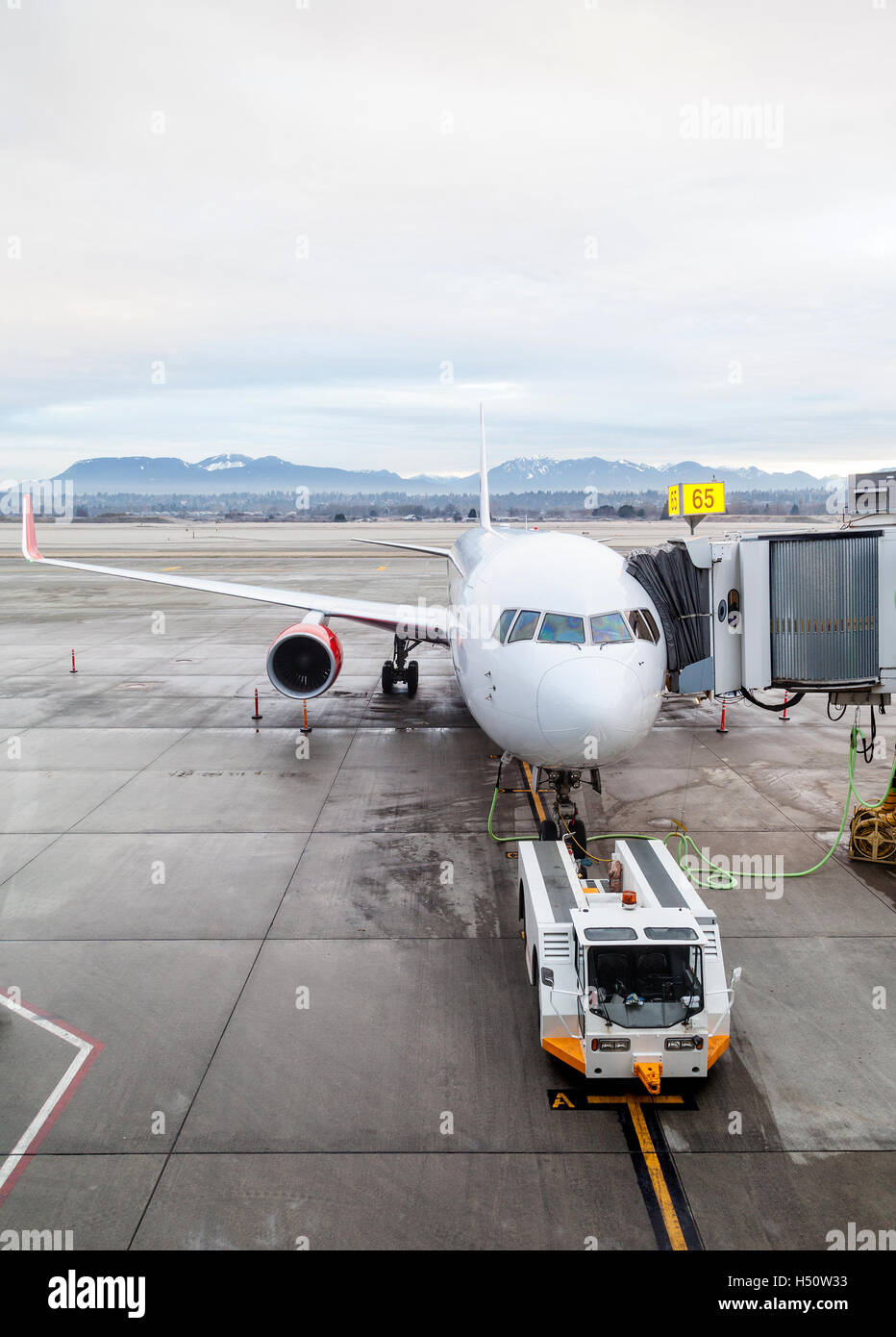 A commercial aircraft on the tarmac being serviced at the passenger terminal of Vancouver International Airport YVR. Stock Photo