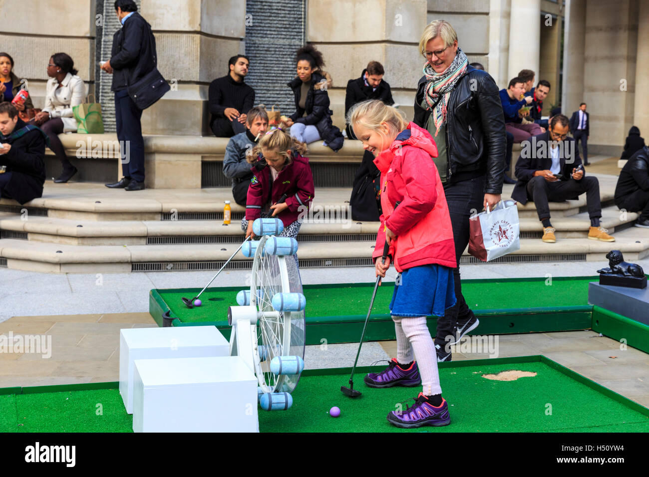 Paternoster Square, City of London, UK, 18th Oct 2016. City workers and visitors enjoy a round of crazy golf on Paternoster Square near St Paul's Cathedral in the City of London. The event is free for all to play and remains at Paternoster Square from 18th Oct to 21st Oct with competitions and a play off cup. The course includes a miniature Tower Bridge, London Eye and other iconic buiildings Credit:  Imageplotter News and Sports/Alamy Live News Stock Photo