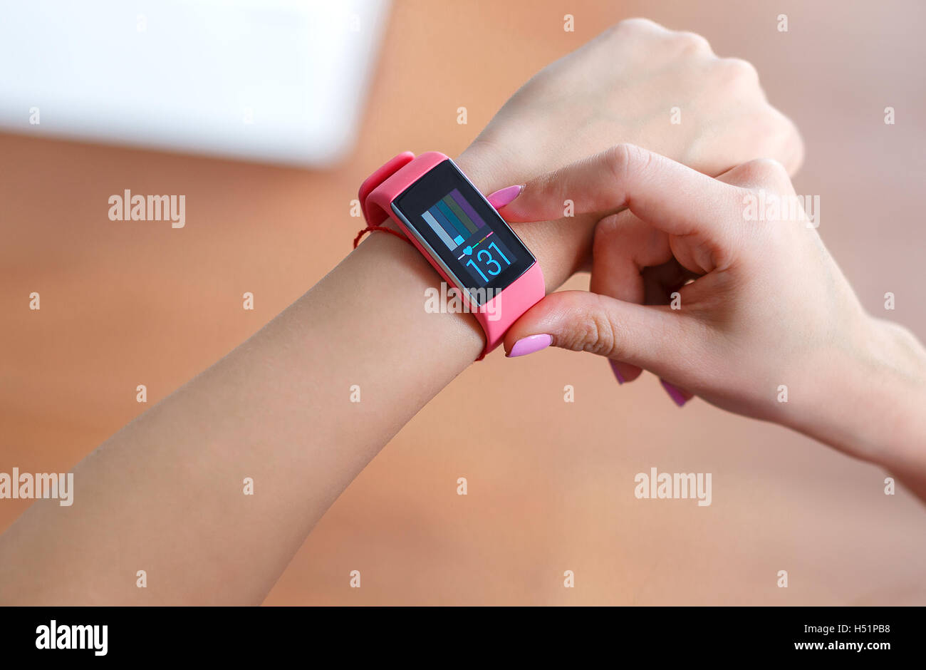 Isolated female hand with pink smartwatch taking pulse after exercising indoor on a light and blured background Stock Photo