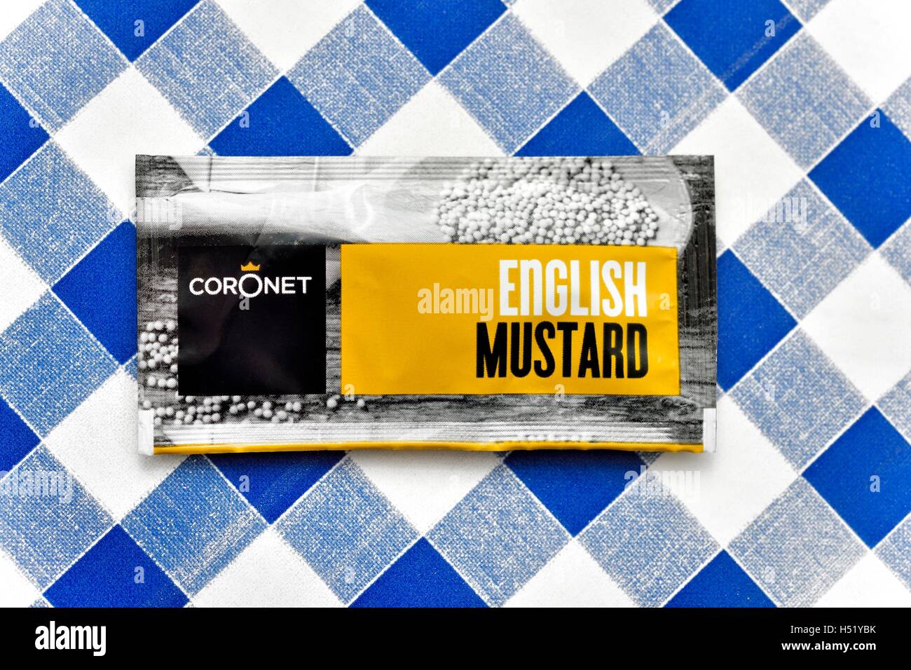 A Sachet of english mustard on a blue gingham background Stock Photo