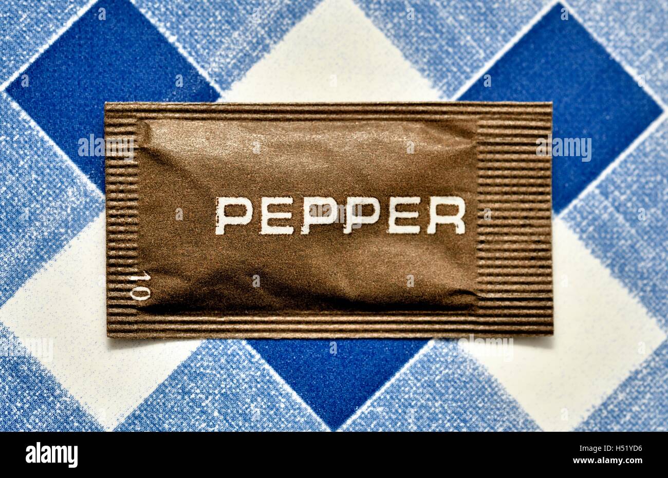 Sachet of catering pepper on a blue gingham background Stock Photo